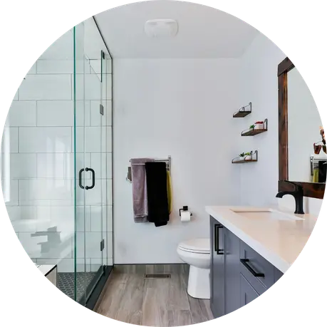 Modern bathroom with glass shower, gray vanity, and wood-look flooring. Timberline Build Co bathroom remodel.