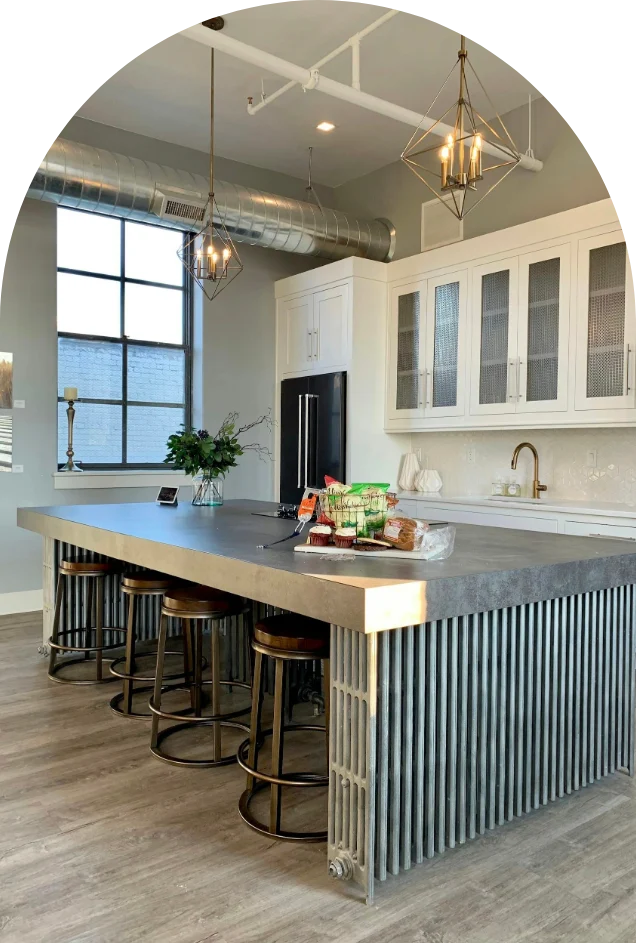 Modern industrial kitchen island with seating, radiator detail, and pendant lighting.