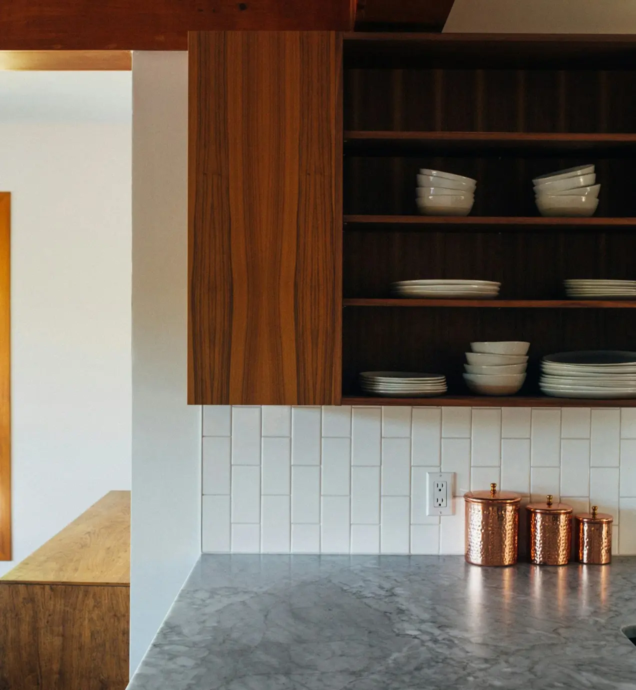 Orange County kitchen remodel: Wood cabinets, marble countertop, white tile backsplash, and copper canisters.