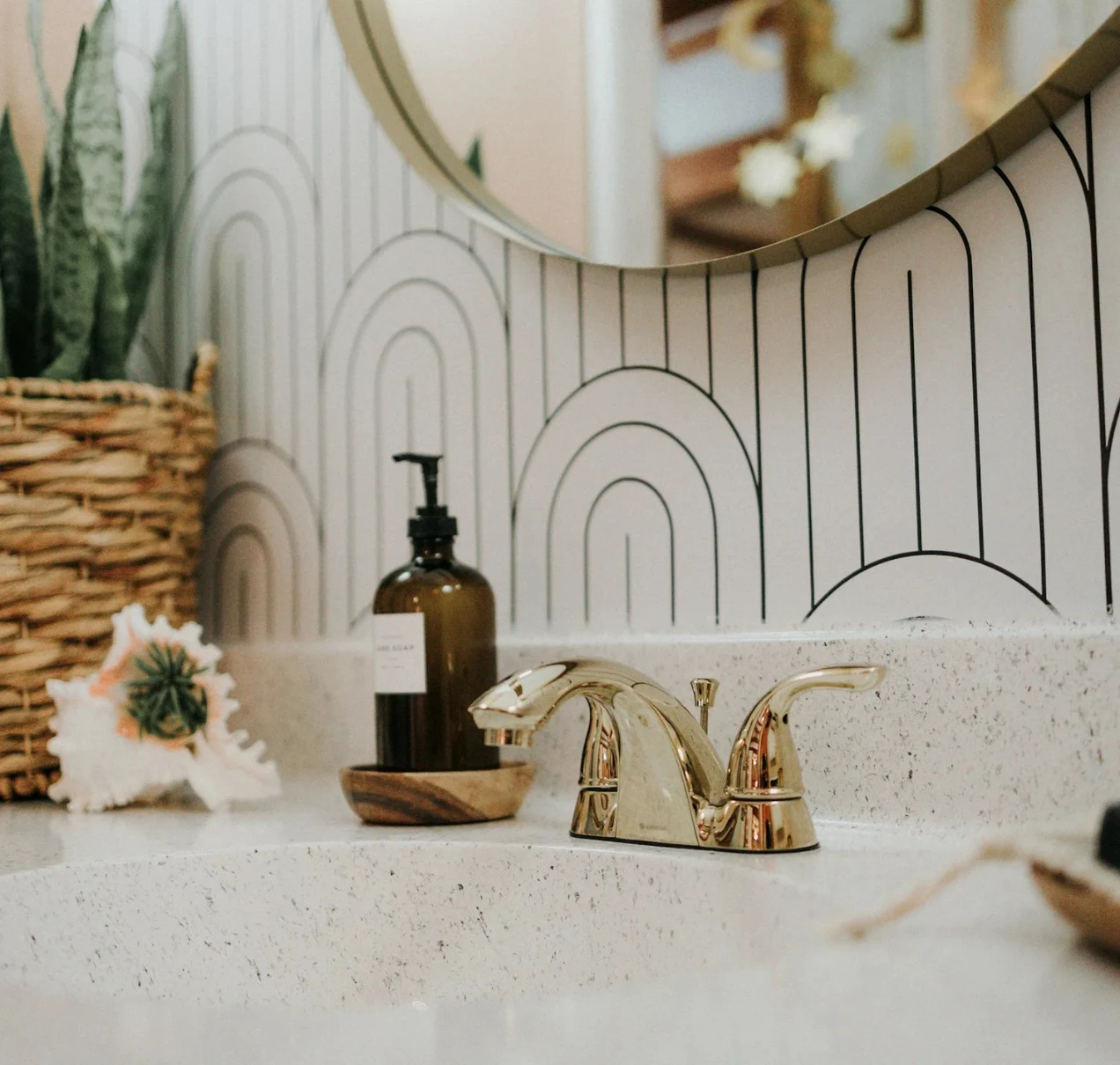 Bathroom Remodeling Dana Point | Luxury & Functional Bathroom Renovations — Timberline Build Co 2 Bathroom sink with gold faucet, patterned wallpaper, soap dispenser, and decorative seashell.