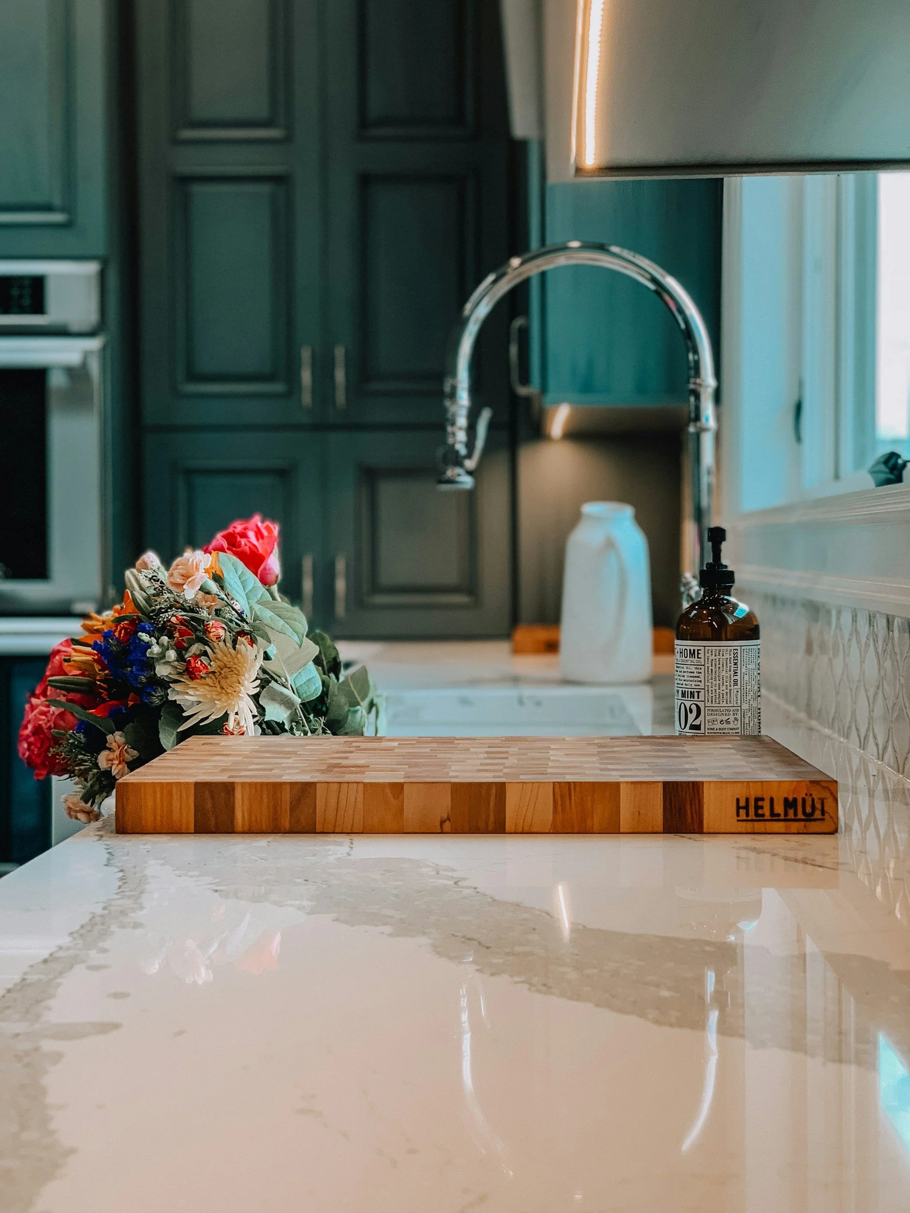 Custom kitchen remodel: flowers, cutting board, and soap by the sink.