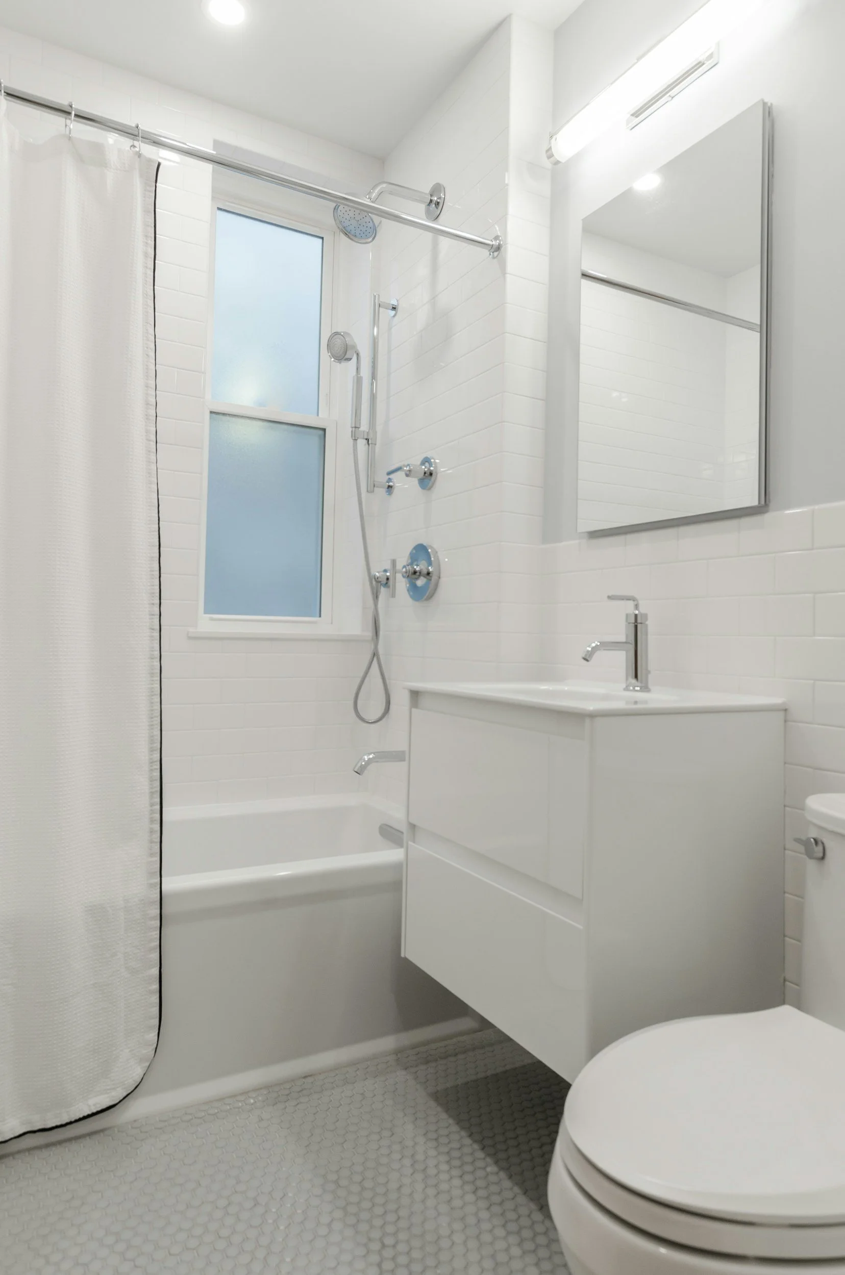 Modern white bathroom with subway tile, shower, and floating vanity in San Juan Capistrano.