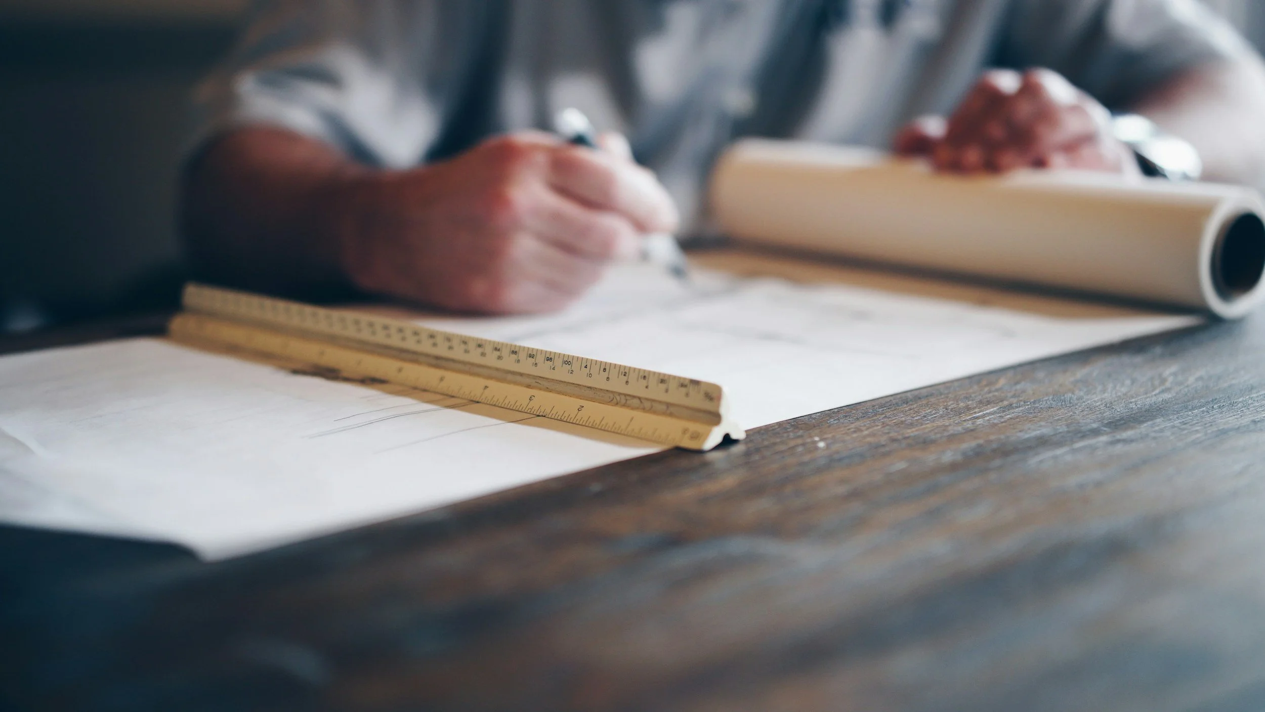 Comprehensive Guide to General Contracting: Local Services, Costs, & Hiring Tips 3 Architect drawing blueprints with ruler on a wooden table, general contracting concept.