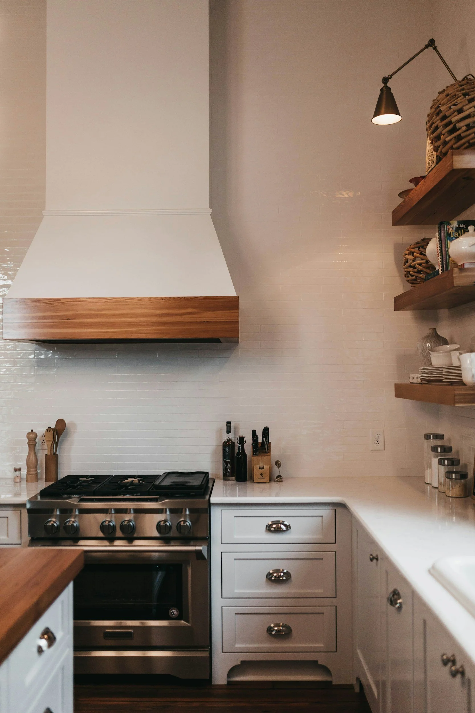 Modern kitchen with white cabinets, wood accents, and stainless steel stove.