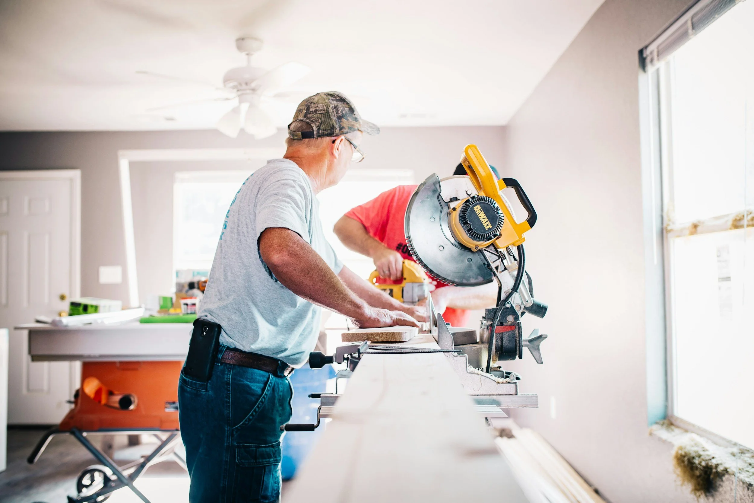 Comprehensive Guide to General Contracting: Local Services, Costs, & Hiring Tips 5 Two contractors using a miter saw to cut wood for a general contracting project.