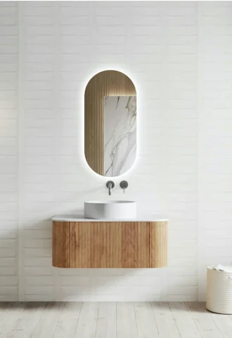 Modern bathroom renovation with wood vanity, vessel sink, and oval lighted mirror. High-end bathroom design.